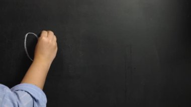 A woman's hand writes the word Omicron in white chalk on a black board. Omicron is a variant of the Covid-19 coronavirus infection
