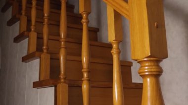 Mavi bornozlu bir çocuk, pantolon ve çoraplar ikinci kattan ahşap merdivenlerden iniyor. Yakın plan.