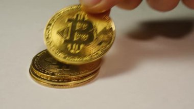 Bir adamın eli beyaz arka planda bir sütuna Bitcoin şifreli para yığıyor.