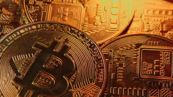 Bitcoin monete criptovaluta primo piano con bagliori di luce arancione che li attraversa. La fotocamera ingrandisce senza intoppi. Monete BTC su sfondo scuro. — Video Stock