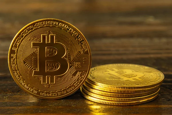Koyu ahşap arka planda BTC altın sikkeleri. Bitcoin şifreli para birimi. Bir madeni para ayakta duruyor ve beş tane de yığınla var. Engelleme teknolojisi. Yakın plan.