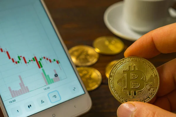 Männerfinger Mit Einer Bitcoin Münze Neben Einem Smartphone Mit Einer Stockbild