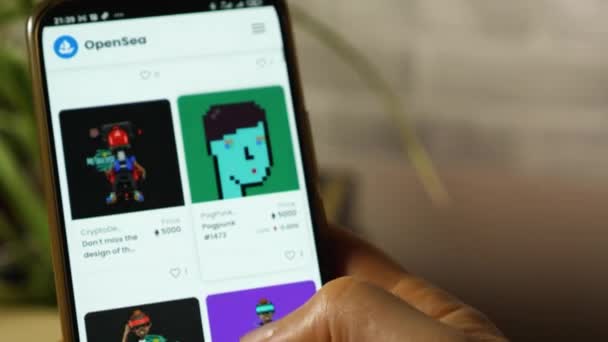 Detailní záběr osoby prstem škrábe na obrazovce smartphonu s obrázky digitálního umění na stránkách OpenSia. Zobrazení tokenu NFT. — Stock video