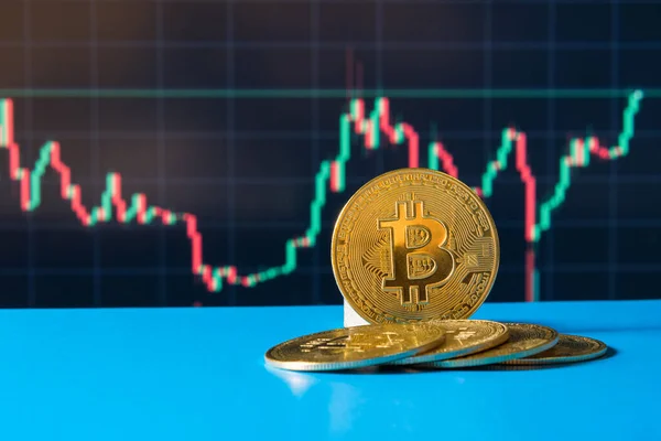 Arkalarındaki BTC madeni parasının mavi arka planında bitcoin kriptosu değerindeki yükseliş ve düşüşün grafiği var. Engelleme teknolojisi