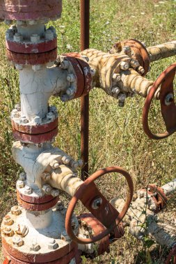 Petrol üretimi bittikten sonra terk edilen kapakçıklı ve boyalı borular. Çevre kirliliği