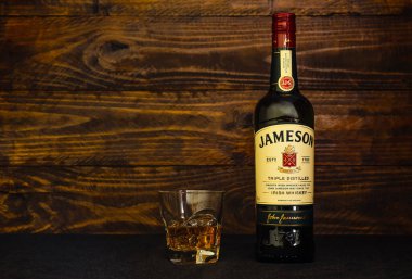 Bir şişe Jameson İrlanda viskisi ve koyu ahşap arka planda buzlu bir bardak. Jameson viskisi yenilikçi yaklaşımı nedeniyle dünyadaki en hafif viskidir. Rusya, Krasnodar, 11 Aralık 2021