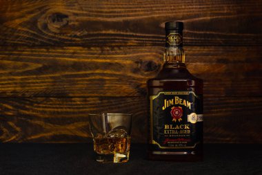 Bir şişe Jim Beam Black American Whiskey ve koyu ahşap arka planda buzlu cam. Amerikan meşe fıçılarında yıllanmış kaliteli bir burbon. Rusya, Krasnodar, 11 Aralık 2021