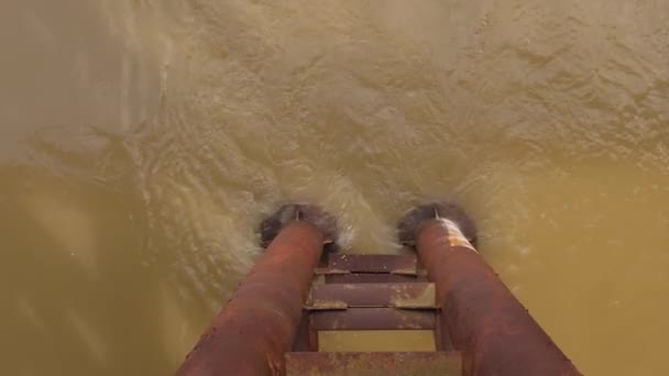 Roestige metalen brug pyloon tegen de achtergrond van een modderige rivier met bruin water. Zicht van bovenaf. modderige rivier tijdens een overstroming. — Stockvideo