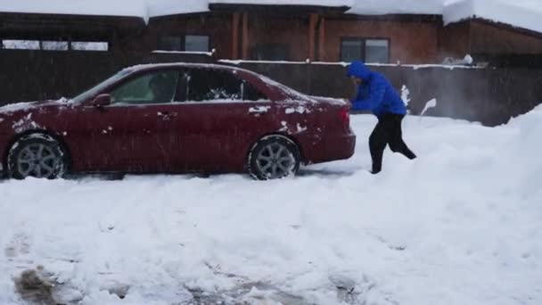 Ein Mann Blauer Jacke Schiebt Ein Rotes Auto Eine Verschneite — Stockvideo