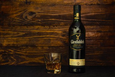 Bir şişe 12 yıllık Glenfiddich viskisi ve koyu ahşap arka planda buzlu bir bardak. Tüm dünyada popüler, prestijli tek malt viski. Rusya, Krasnodar, 11 Aralık 2021