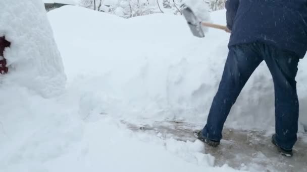 ジャケットとジーンズの男が通りから雪を掘っている 雪の嵐の後 冬のエリアをきれいにします 背景の降雪 — ストック動画