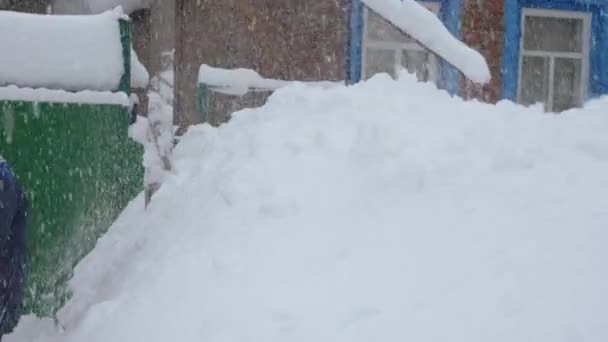 一个人用铲子把雪扔在一堆大雪上 后面是一座红砖房子和雪地 — 图库视频影像