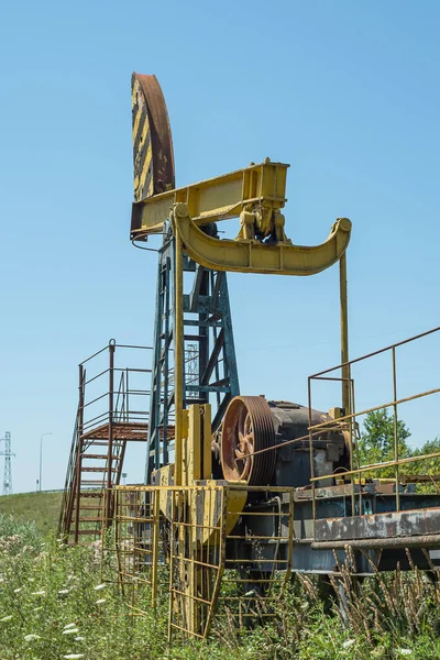 蓝色天空映衬下的田野里一个古老的黄色停止了石油钻机 石油工业衰败的概念 石油用完了 石油钻机生锈了 — 图库照片
