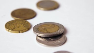 Farklı ülkelerden gelen paralar yavaş çekimde beyaz arka plana düşer. Yakın plan. Küresel finansal kriz kavramı