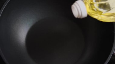 Siyah bir tavaya ayçiçeği yağı dök. Üst manzara, yakın plan. Asya tarzında yemek pişirme
