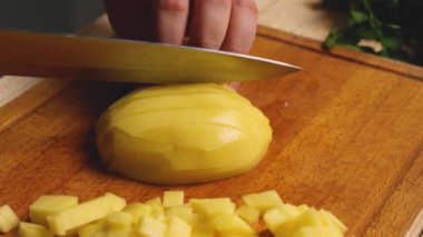 Kesme tahtasının üzerinde patatesleri doğrayan bir bıçakla bir kadının ellerine yakın çekim.