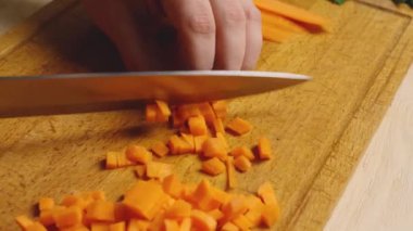 Tahta bir kesme tahtasının üzerinde havuç doğrama ve doğrama yakın çekim. Her gün sağlıklı ve sağlıklı yiyecekler. Ev yemekleri, diyet yemekleri.