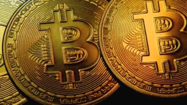 Bitcoin kripto para biriminin güzel sarı ışıklı yakın plan görüntüleri. Kamera hareketi soldan sağa doğru. Koyu arkaplanda BTC madeni para