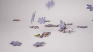 Yapboz parçalarının yakın çekimleri yavaş çekimde beyaz bir arka plana düşer ve tüm kareyi kendileriyle doldurur..