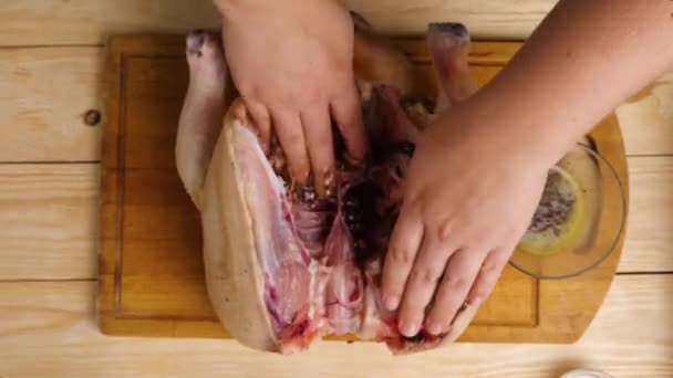 Close-up of a womans hands rubbing spices inside a chicken carcass. The spread out chicken is lying on the cutting board. Top view. Cooking at home. — Stock Video