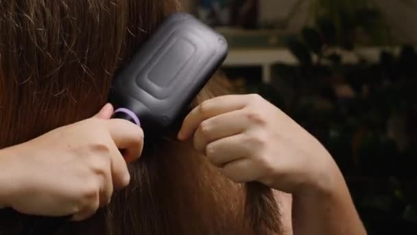Крупным Планом Руки Девушки Расчесывающей Волосы Специальной Электрической Распрямляющей Щеткой — стоковое видео