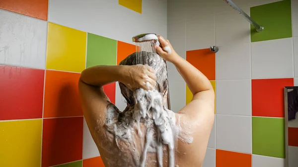 一个女人在浴室里洗头 洗发水从她乌黑的头发上流了出来 泡沫顺着她的后背流下来 头发护理概念 — 图库照片