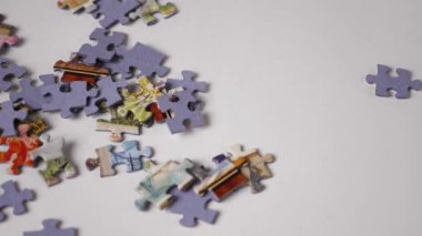 Bulmacanın parçaları beyaz arka plana düşer. Yakın plan. Yavaş çekim