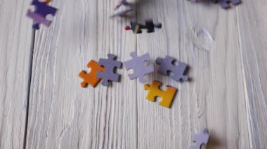 Renkli yapboz parçalarının yakın çekimi beyaz, kırmızı, ahşap bir zemine düşüyor. Yavaş çekim