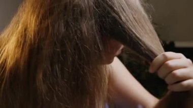 Yavaş çekim saçı özel bir elektrikli fırçayla tarıyor. Kadın saçına zarar vermeyen seramik ısıtılmış fırça kullanıyor. Yakın plan.