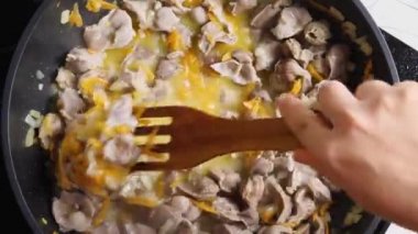 Tavada sebzeli tavuk güveci karıştıran ahşap bir spatulayla bir kadının elinin en üst görüntüsü. Yakın plan. Asya tarzında yemek pişirme