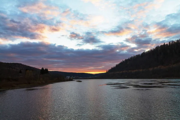 Sonbaharda gün batımından sonra nehir dağlar ve ormanın arka planına karşı. 