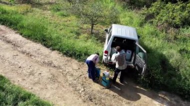 İki tarımcı toprağın yanındaki bir arabada, bir tanka ot ilacı yüklüyor. İHA görüntüsü. 4 bin. Bargota, Navarre, İspanya, Avrupa.