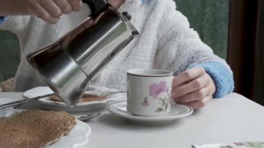 Woman pouring coffee from coffee pot into cup at breakfast. Close-up. 4K.