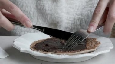 having buckwheat pancakes with cocoa cream for breakfast. Close-up of plate and pancakes. 4K.