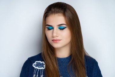 Parlak mavi makyajlı güzel bir kız. Büyük gözler, gölgelerin gölgesi, doğal ruj. Sıcak örülmüş kazak sonbahar ve kış havalarında sıcak tutar. Uzun kahverengi saçlar parlak ve sağlıklıdır.