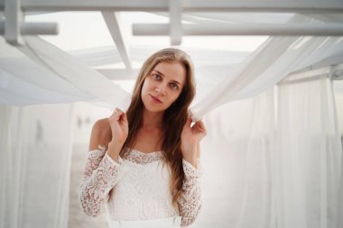 Genç güzel bir kız beyaz bir düğün çadırında duruyor ve elinde şeffaf bir kumaş tutuyor. Doğal Slav güzeli, bej tenli, uzun sarı saçlı. Gelin damadı bekliyor, yalnız düşünceler.