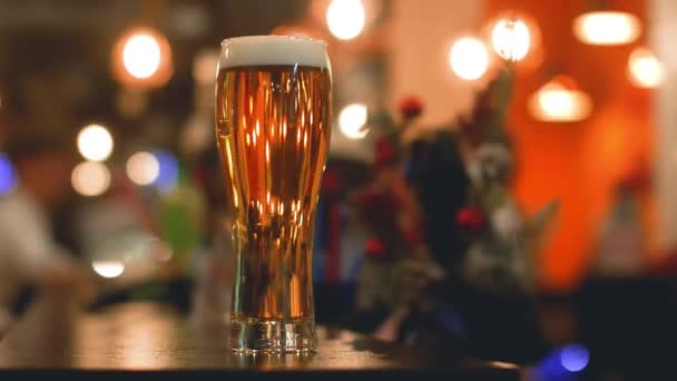 Un vaso de cerveza ligera en un pub oscuro. — Vídeos de Stock