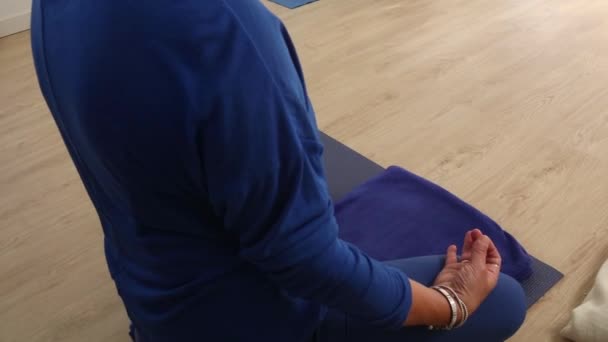 一位身着蓝色衣服的瑜伽老师一边在家里授课 一边把她的手放到了摄像机前 — 图库视频影像