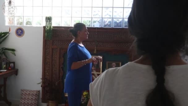 身着蓝色衣服的瑜伽老师在学生面前进行了一项背向运动的热身运动 — 图库视频影像