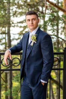Zarif, koyu mavi takım elbiseli yakışıklı bir damat. Şık damat modası.