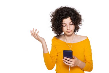 İnançsız bir şekilde cep telefonuna bakan öfkeli genç bir kız. Telefonundaki şok edici mesaja bakan genç, beyaz arka planda izole edilmiş..