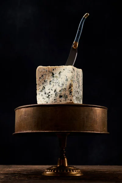 Block of blue mold cheese on dark background. Blue cheese dark rustic food photography.
