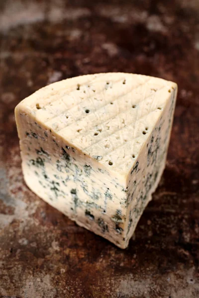 Block of blue mold cheese on dark metal background. Blue cheese dark rustic food photography.