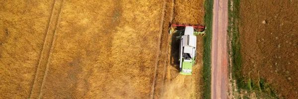 Wheat shortage, high trading prices, stockpiling. Aerial view of a combine harvester at work during harvest time. Agricultural banner.