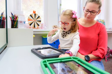 Serebral felçli sözsüz bir kız iletişim kurmak için dijital tablet kullanmayı öğreniyor. Dil geliştirmede zorlanan ya da konuşma aygıtı kullanan insanlar.