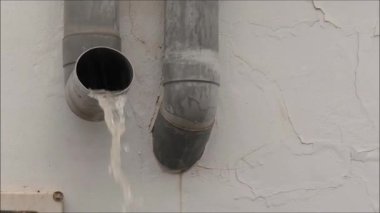 Köy caddesinde sağanak yağmur. Kanalizasyonlardan ve borulardan akan yağmur suyu