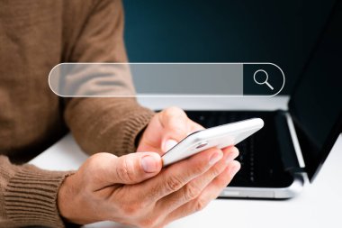 Adam dizüstü bilgisayarla uğraşırken telefonuyla konuşuyor. Boş bir arama çubuğuyla, konsept İnternet Veri Bilgileri Arama Motoru. Arama Motoru Optimizasyonu (SEO) Ağı