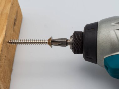 Sağlam ahşap tezgahta bir marangoz elektrikli tornavida kullanır..