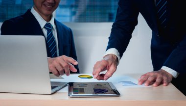 İki işadamı, iş yerinde bir hisse senedi ve iş konsepti gösteren bir bilgisayar tabletine el kaldırıyor..