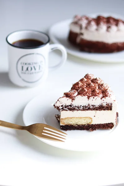 Tiramisu keki ve beyaz bir masada bir fincan çay.